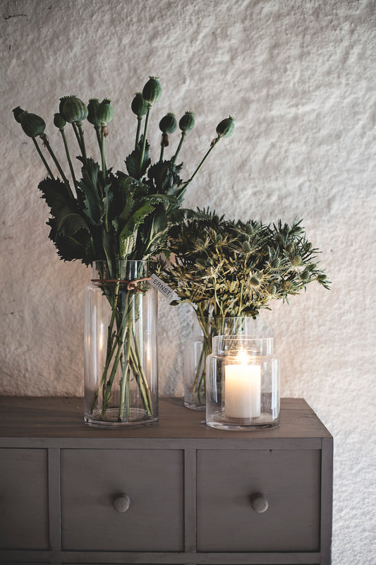 Klar glasvase med læderbånd og blomster i en rolig indretning