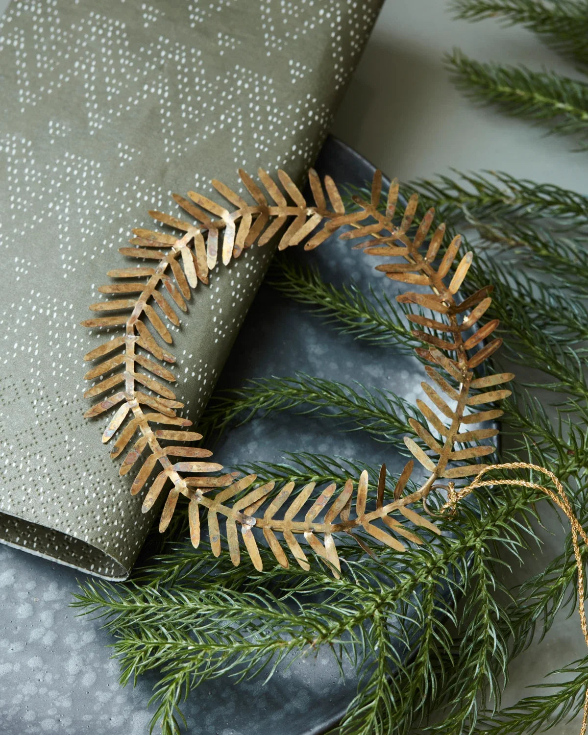 Lamet juleornament i messing formet som en rund krans med små dekorative blade, Ø 9 cm