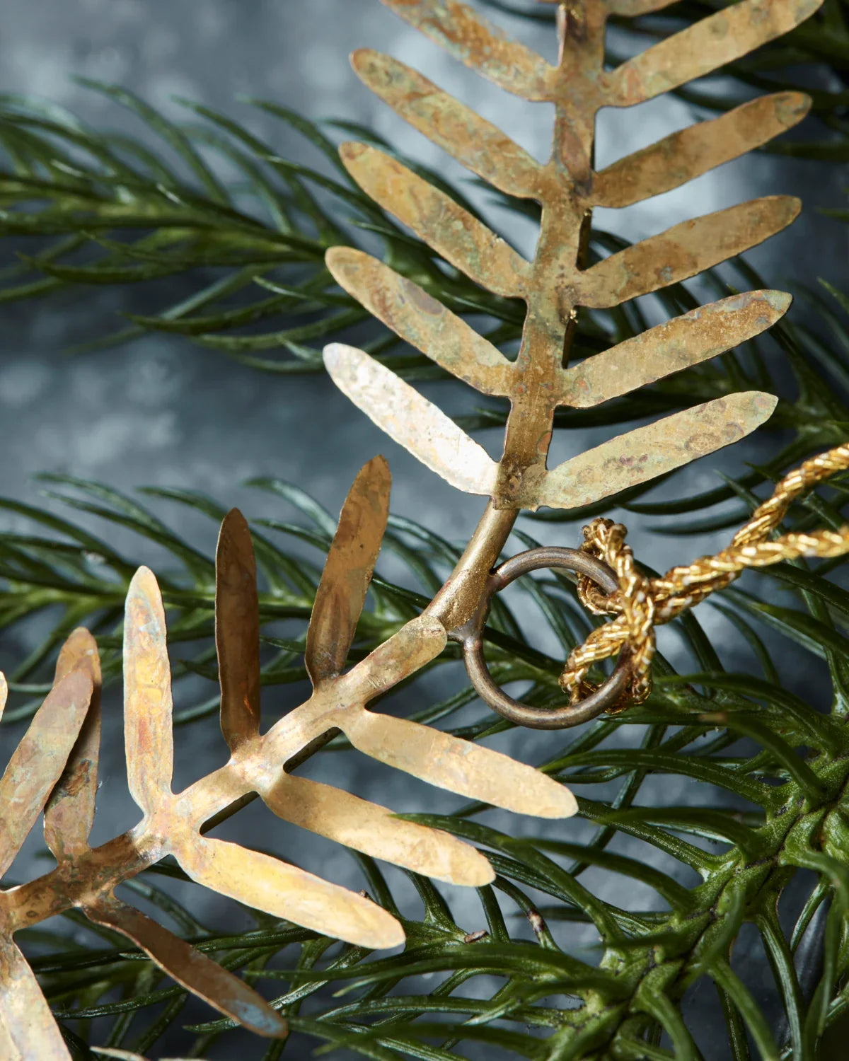 Lamet juleornament i messing formet som en rund krans med små dekorative blade, Ø 9 cm