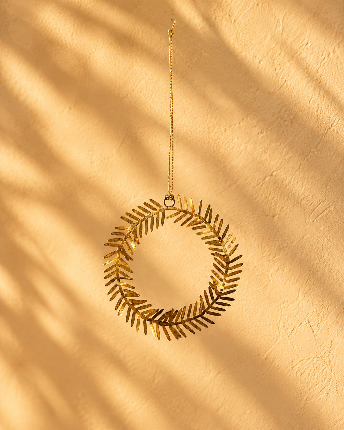Lamet juleornament i messing formet som en rund krans med små dekorative blade, Ø 9 cm